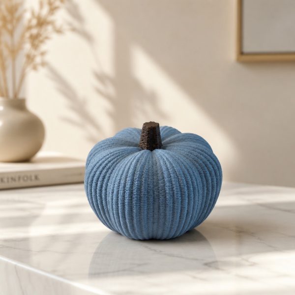 Gerippte Kürbisdekoration in Muted Blue mit dunklem Stiel auf einer hellen Oberfläche