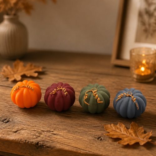 Vier gerippte Mini-Kürbisse in Orange, Bordeaux, Grün und Blau auf einem Holztisch mit Herbstdeko.
