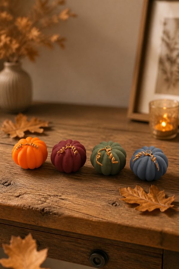 Vier gerippte Mini-Kürbisse in Orange, Bordeaux, Grün und Blau auf einem Holztisch mit Herbstdeko.